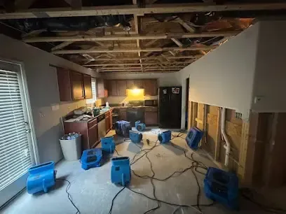 Kitchen and family room with the lower walls opened, the ceiling cut back and blue air movers drying the space