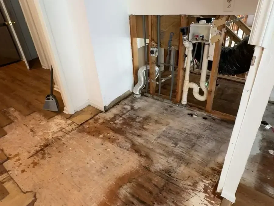 A wall opened up around the plumbing with the soaked flooring pulled away