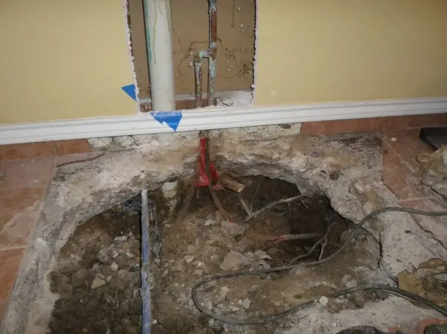 Concrete slab cut open to expose a leaking water line beneath the floor